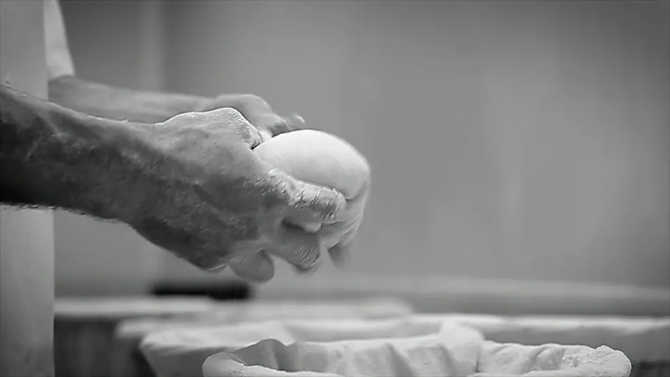 Hands shaping bread dough in an independent bakery
